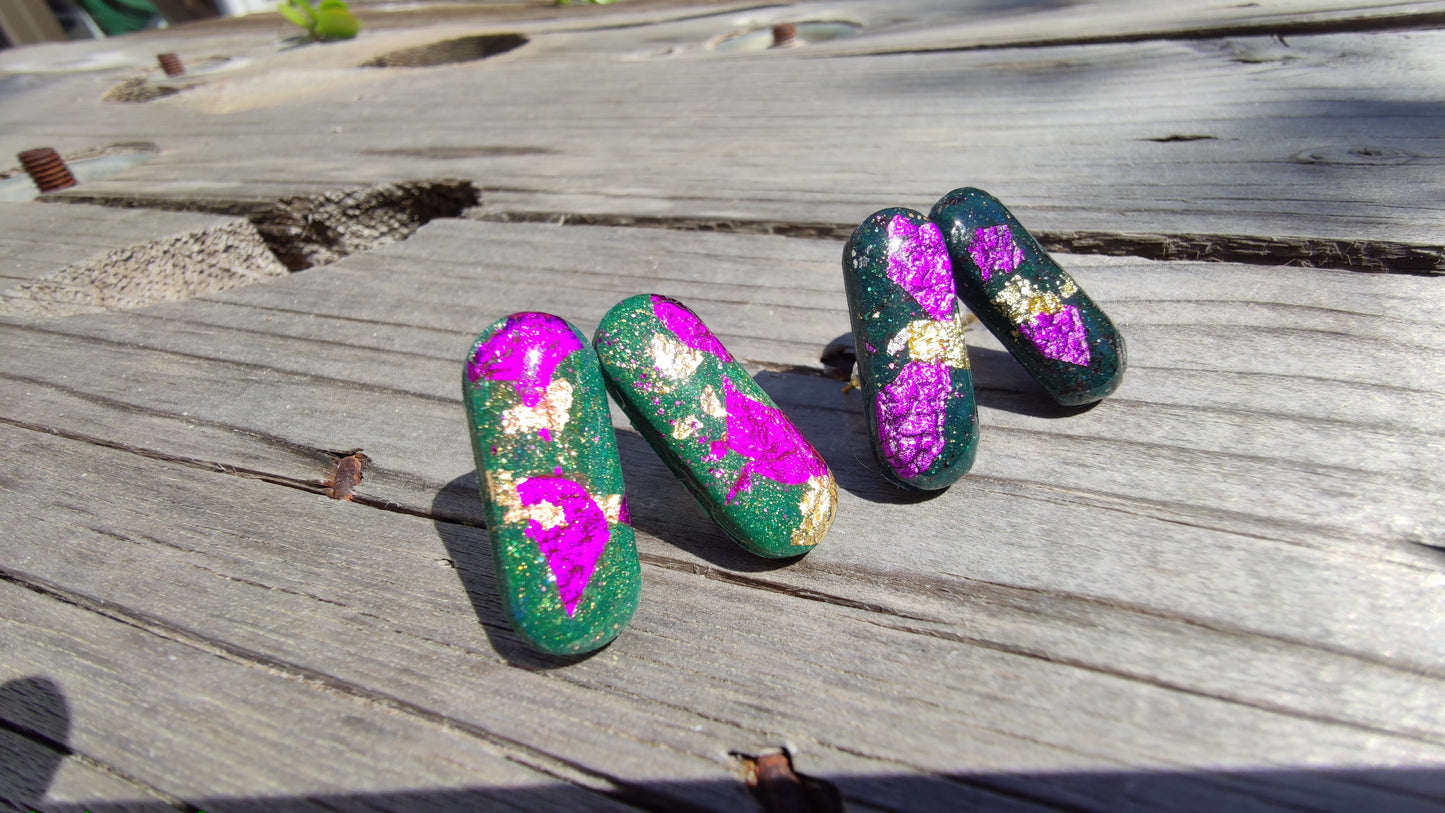 Détail des éclats fuchsia et or sur boucles Astral vert sapin, résine UV brillante