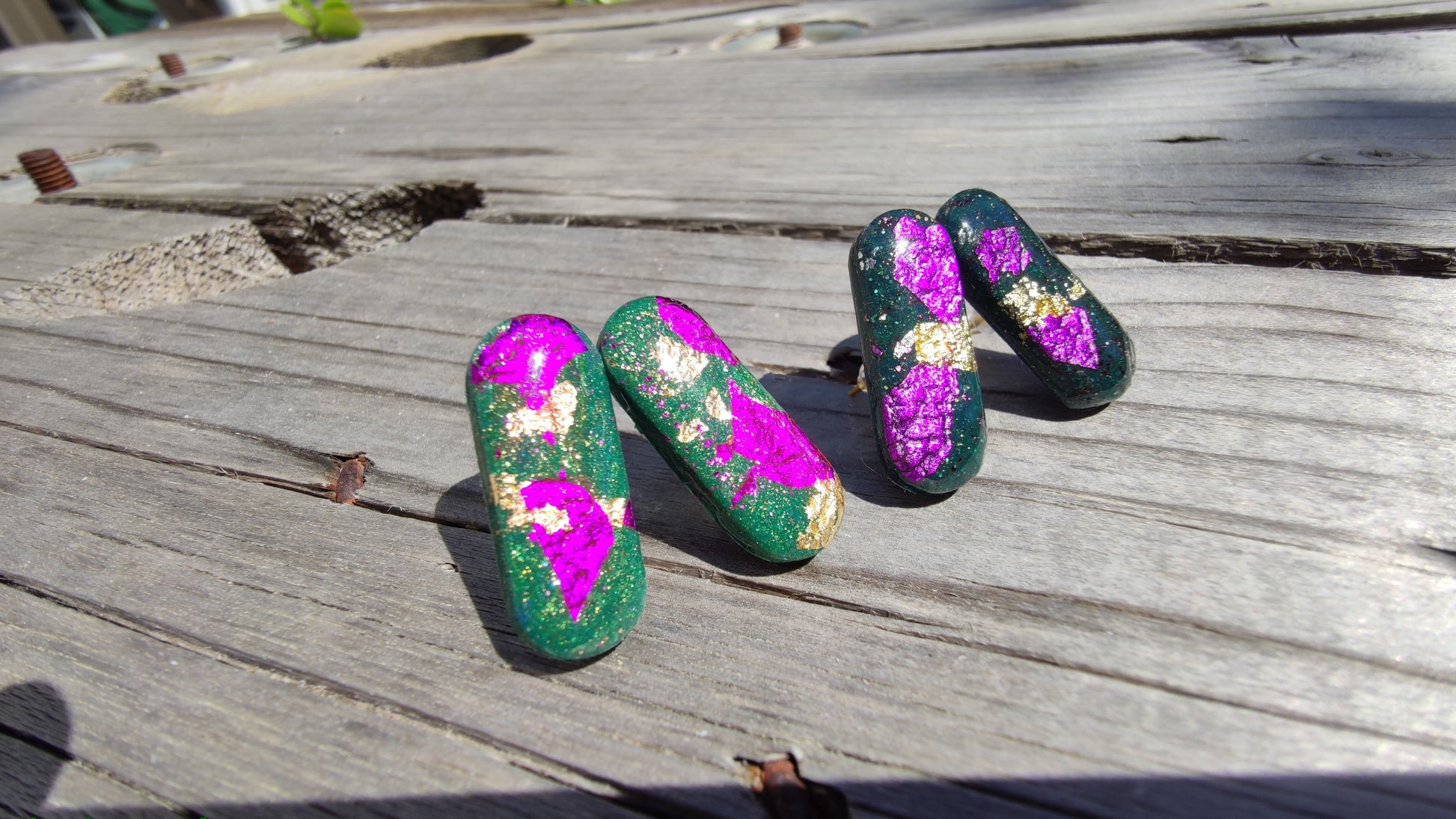 Détail des éclats fuchsia et or sur boucles Astral vert sapin, résine UV brillante